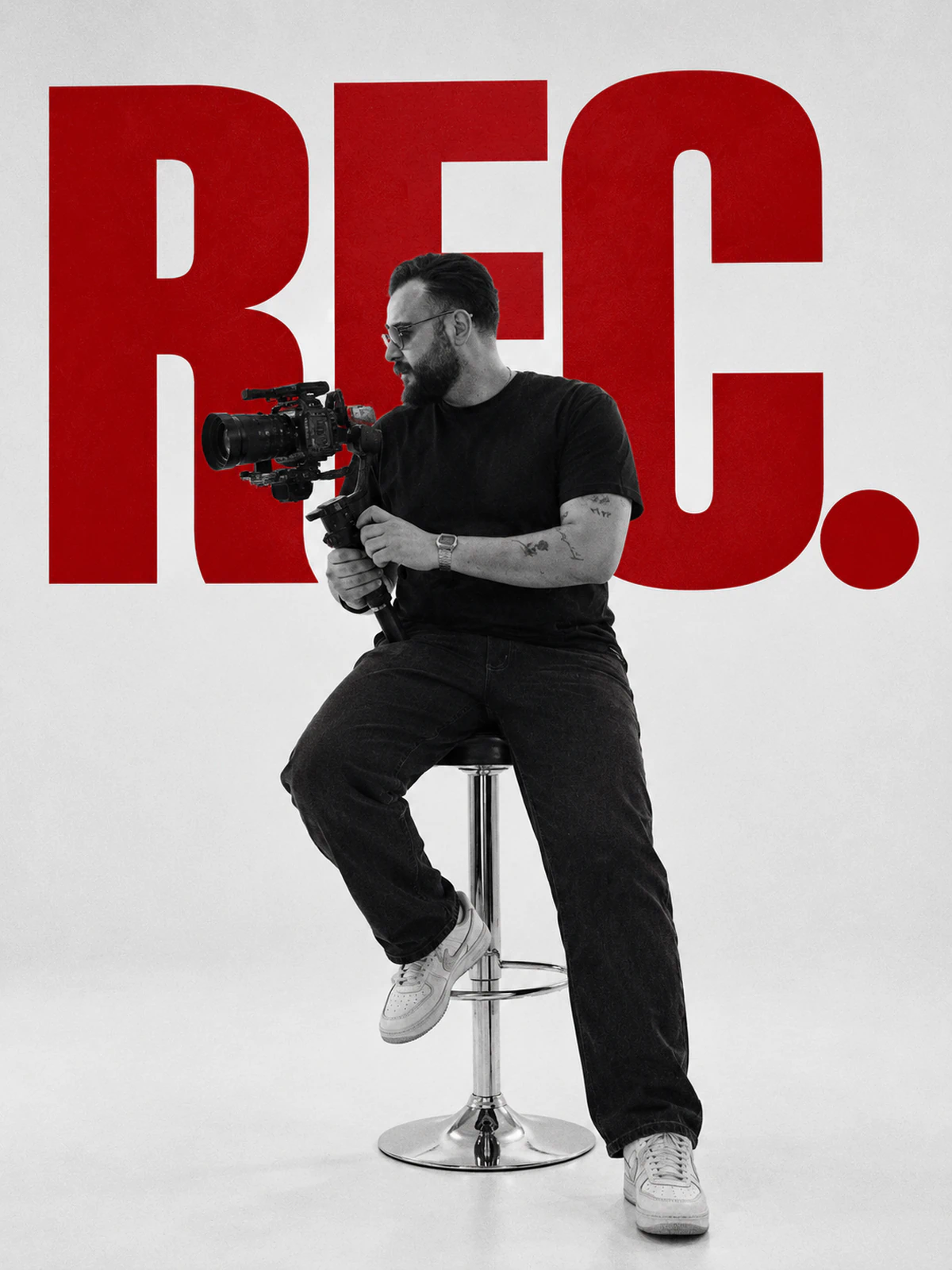Hasan Mahdi holding a cinema camera on a gimbal in front of a red REC backdrop