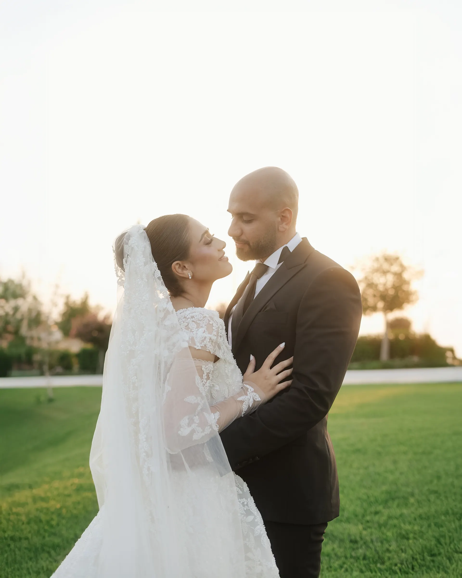 Bride and groom outdoors on a green lawn in warm natural light